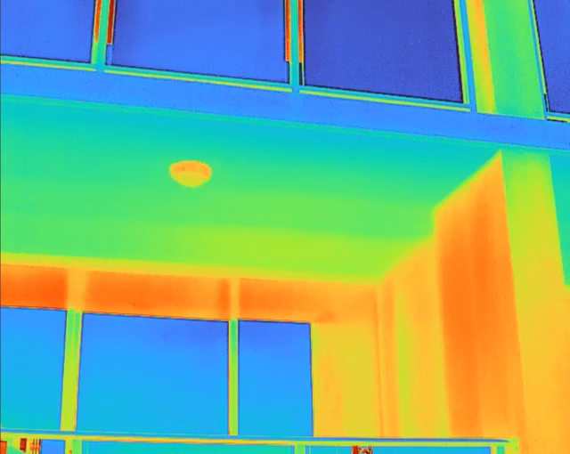 Thermal mapping of a balcony soffit identifying hot spots and heat accumulation near the building's exterior glazing.