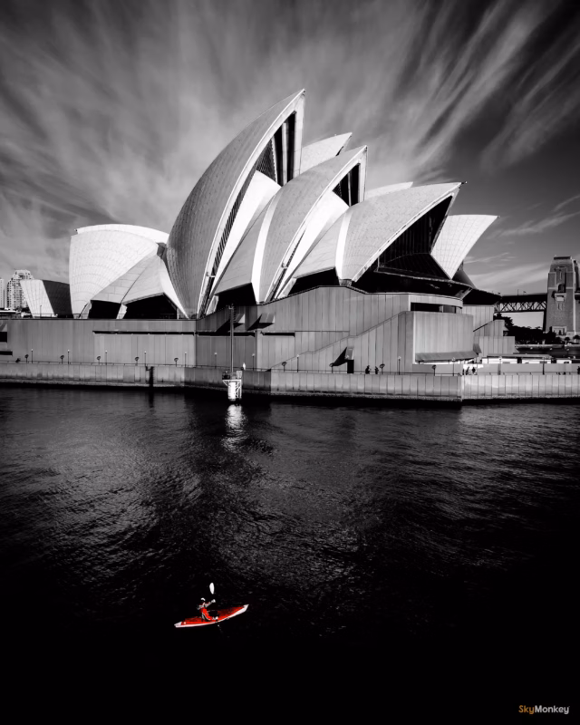 Creative photography of the Sydney Opera House in black and white, with an in-colour kayak over Sydney Harbour, taken by Sky Monkey